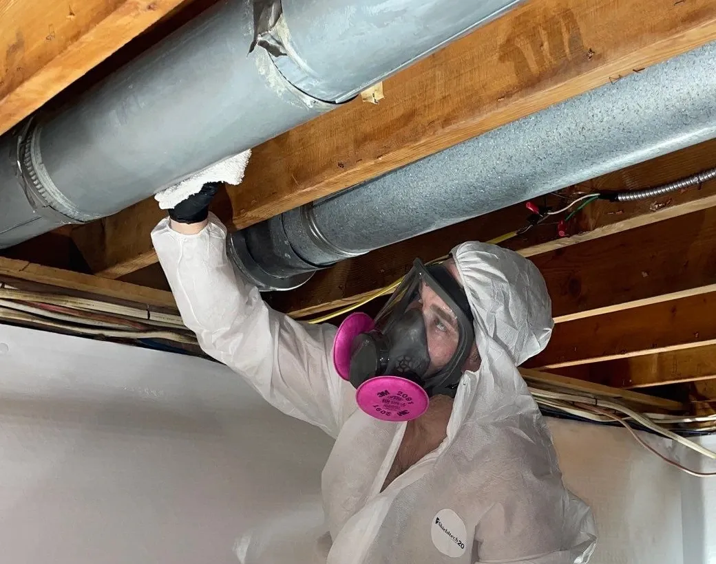 worker wiping vent in ceiling