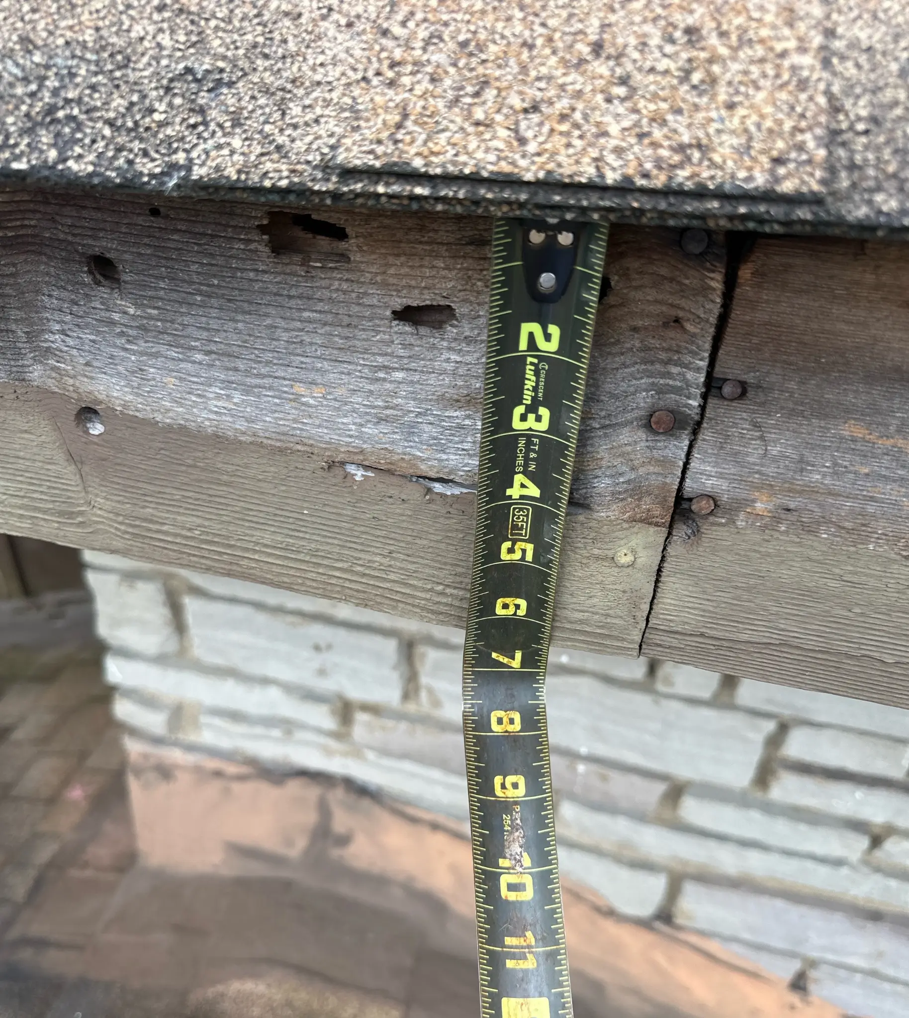 A roofing estimator is using his tape measure during the roof inspection process.