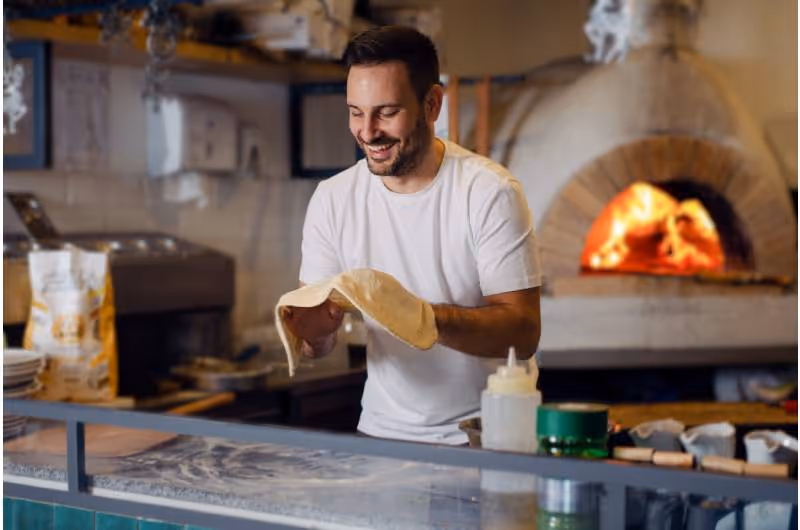 Joven con masa de pizza en las manos
