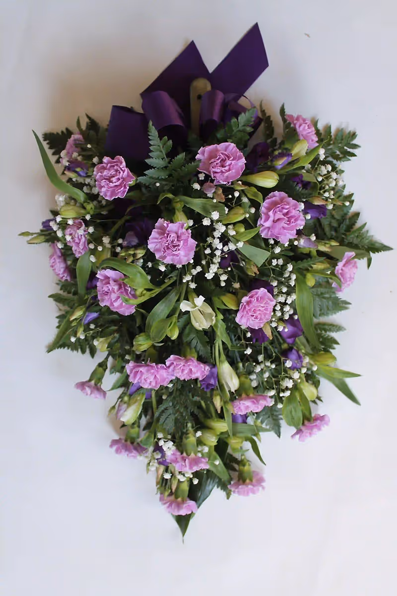 Violeteista neilikoista ja inkaliljoista sidottu surulaite.