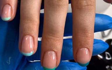 Close-up of fingers with a French manicure featuring pastel green tips on natural nails.