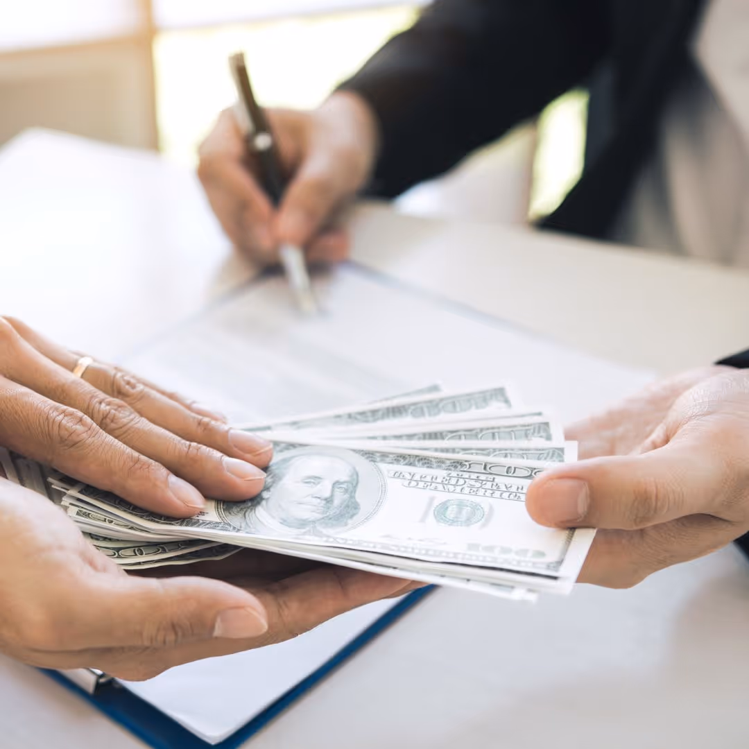 people exchanging cash over paperwork