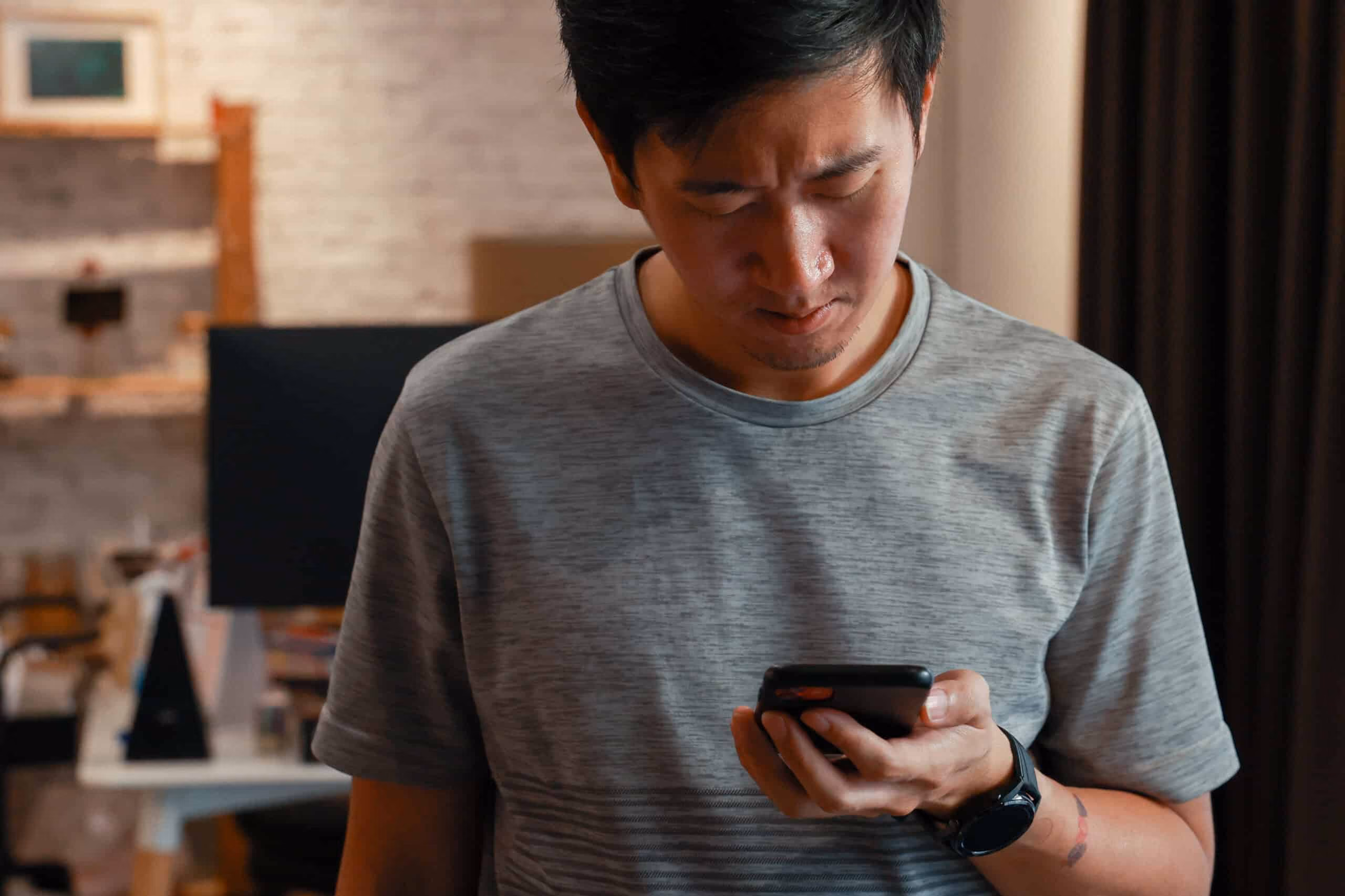 A man angrily looking at his cell phone at home