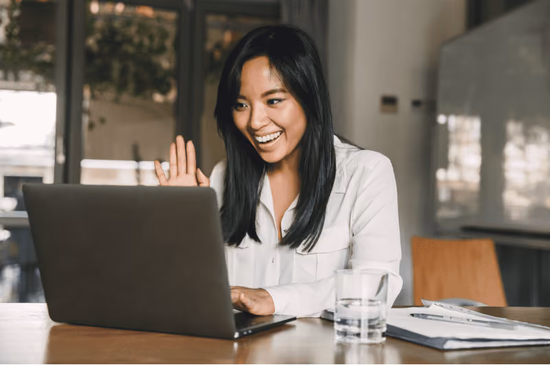 Woman in a white shirt talking on a laptop