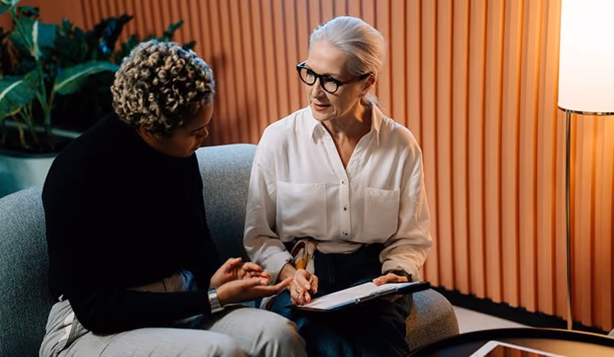 A woman in a black sweater working with a therapist in a white button down