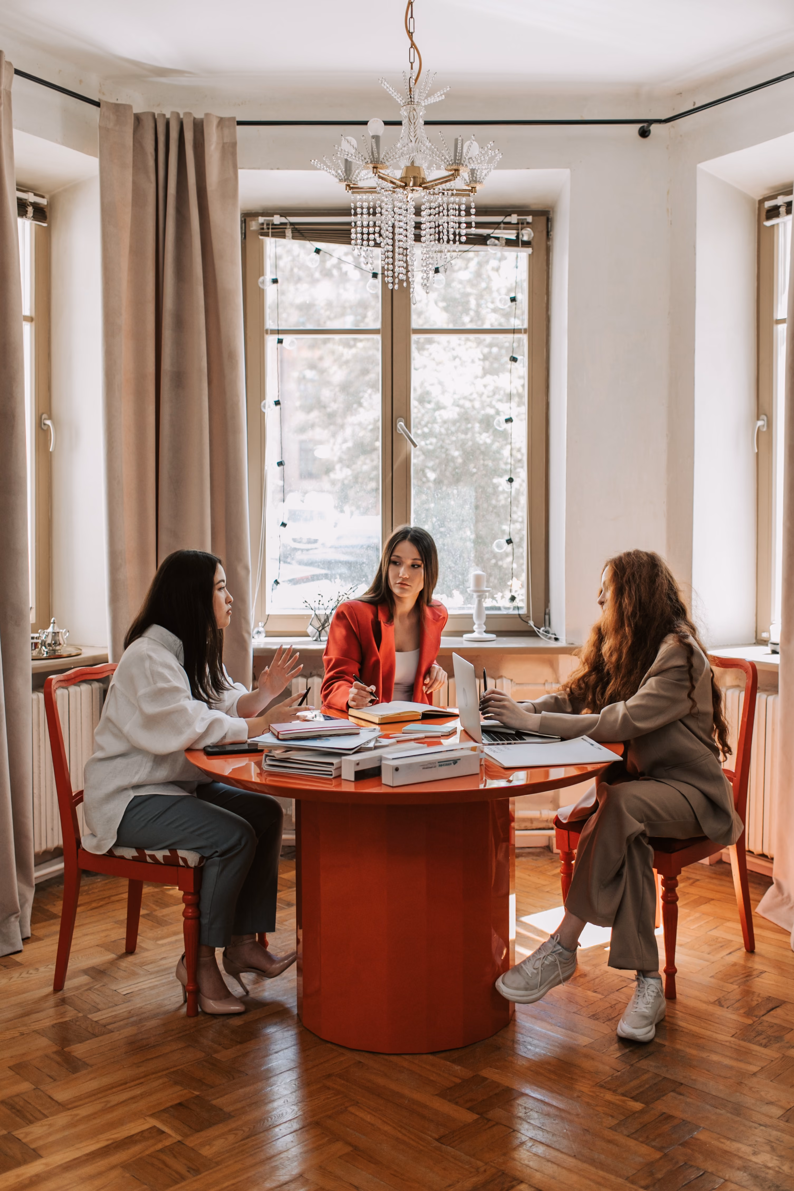 Women leaders sitting at a table having a discussion with notebooks and paperwork on the table