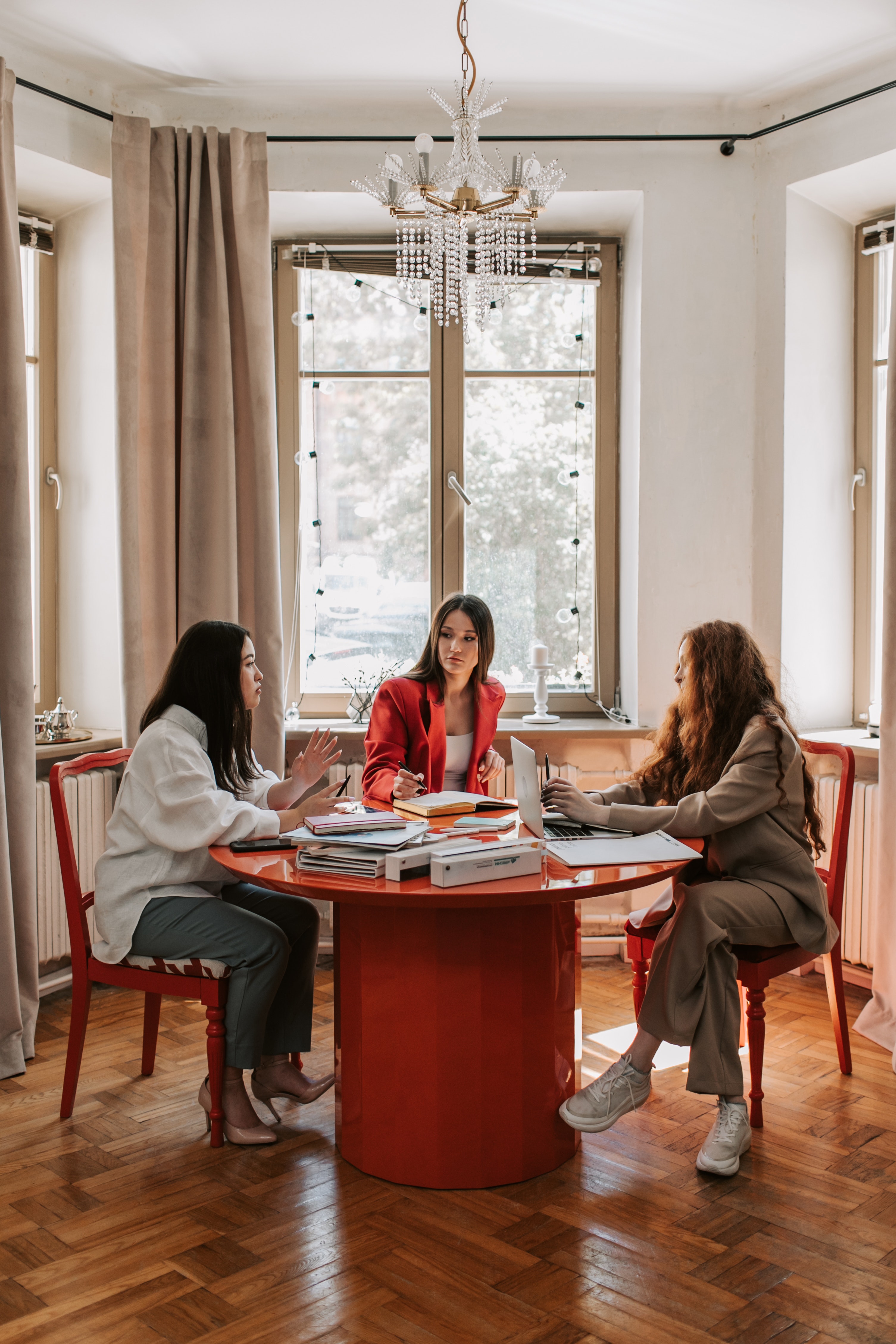 Women leaders sitting at a table having a discussion with notebooks and paperwork on the table