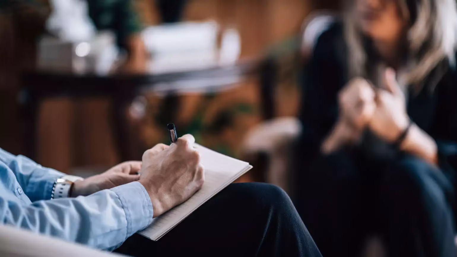 A close up of a man taking notes in a notebook