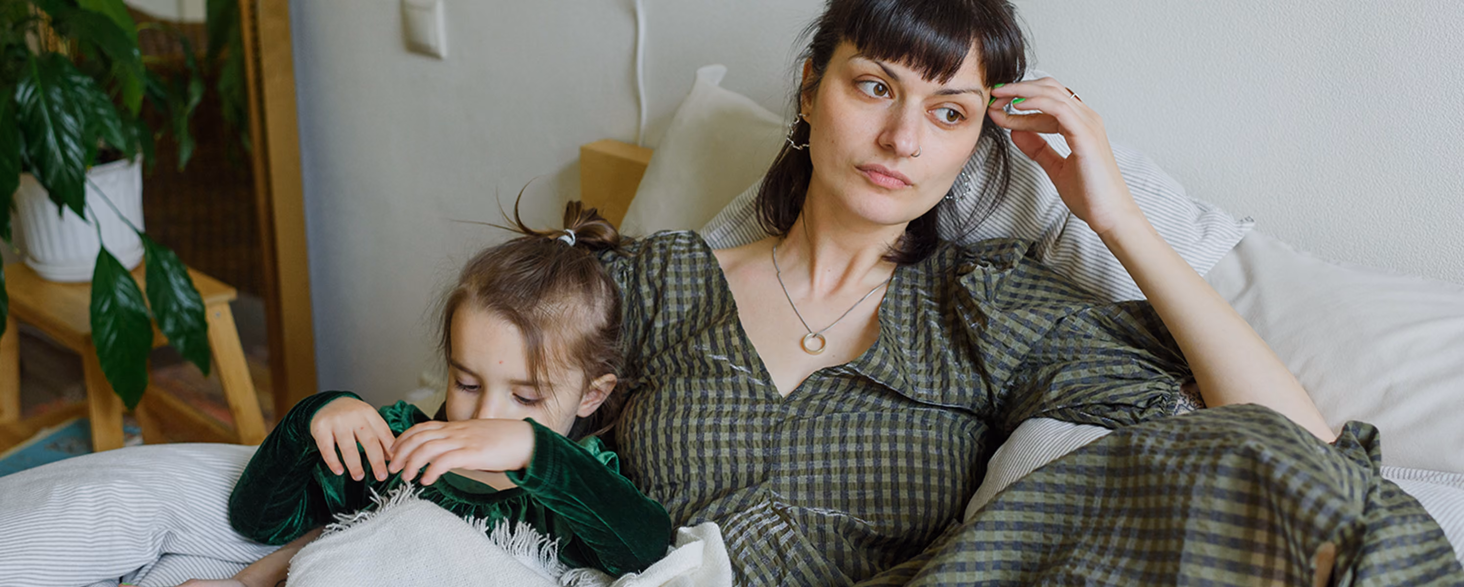 A woman in a green dress looking distraught while holding her daughter