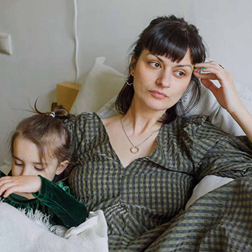 A woman in a green dress looking distraught while holding her daughter