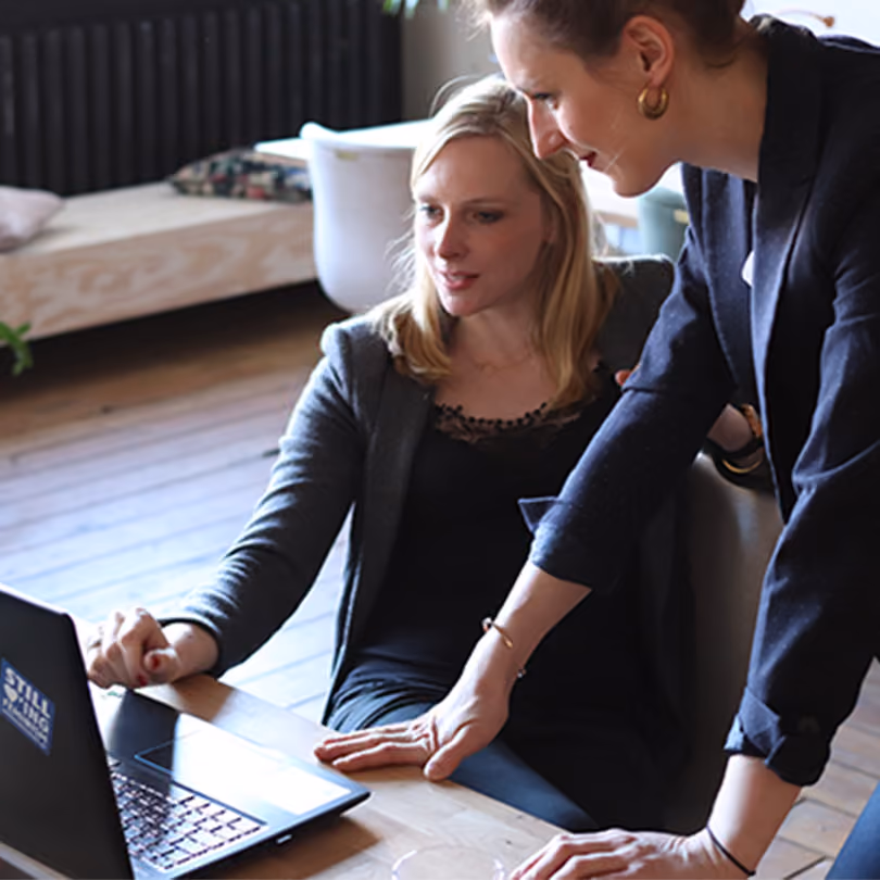 Two women in the workplace looking at a document on a laptop