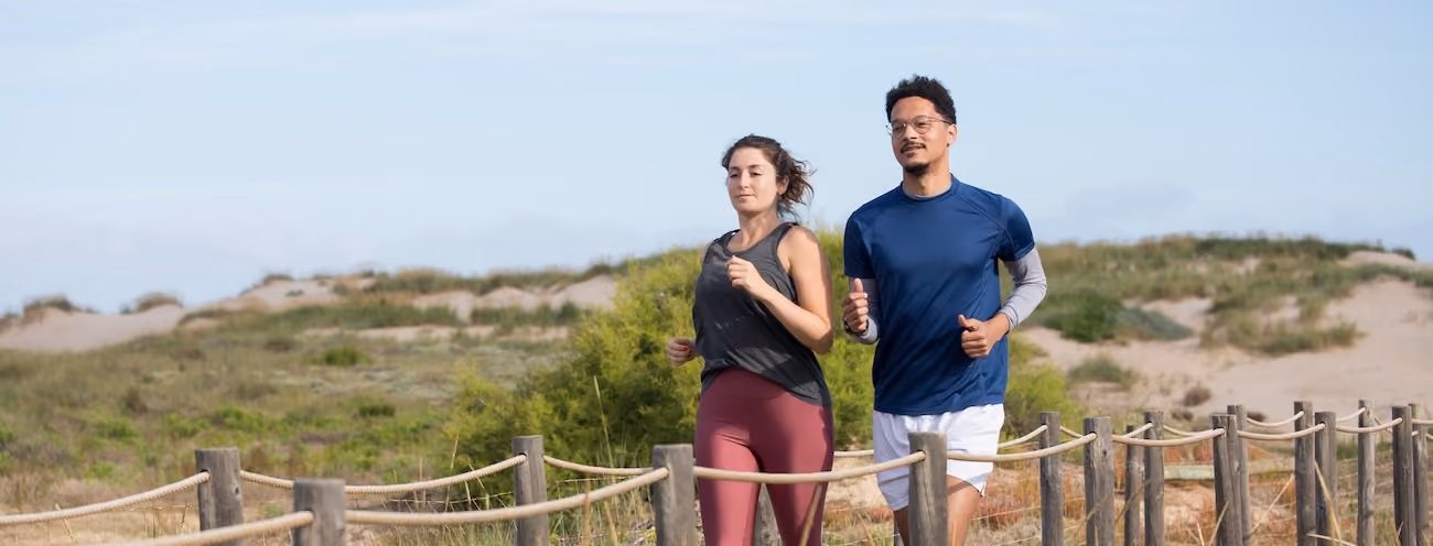 A man and a woman jogging on a nature trail during the day