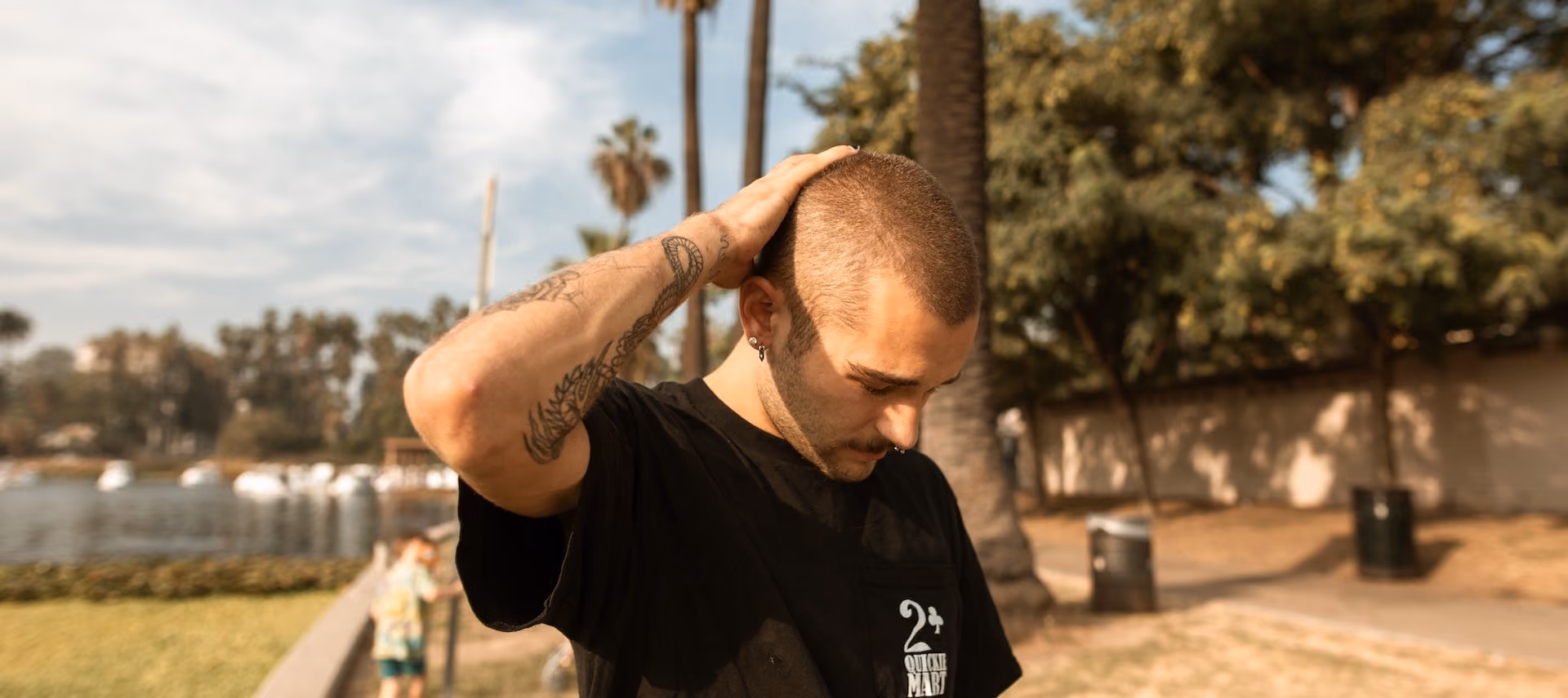 Man with a pierced nose in a black shirt in the park struggling with his mental health