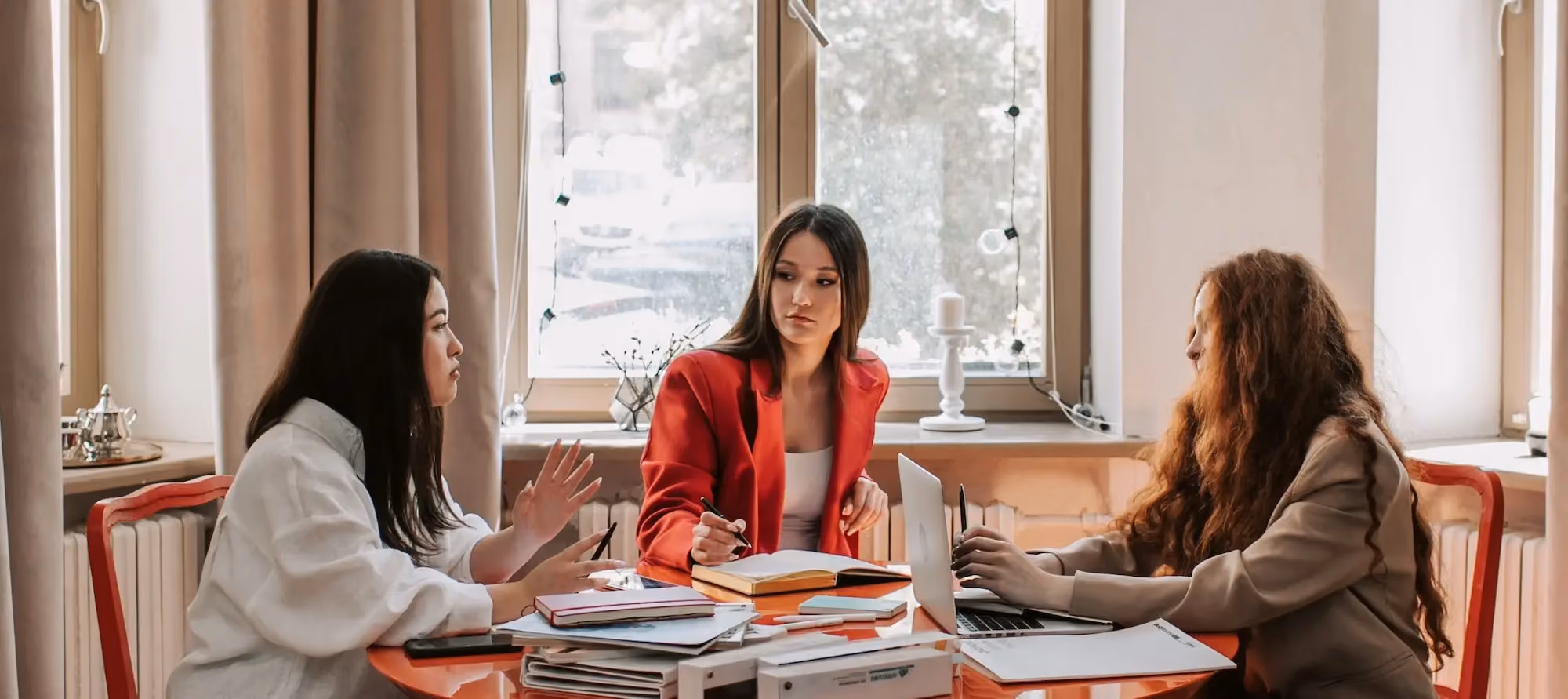 Women leaders sitting at a table having a discussion with notebooks and paperwork on the table