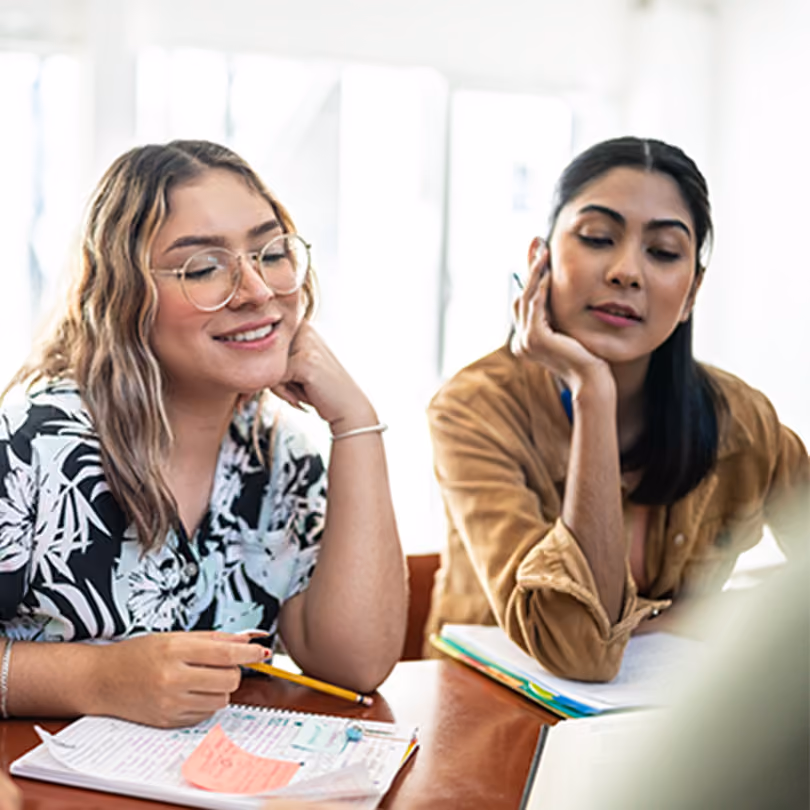 Woman in glasses working with another Gen Z woman on a project