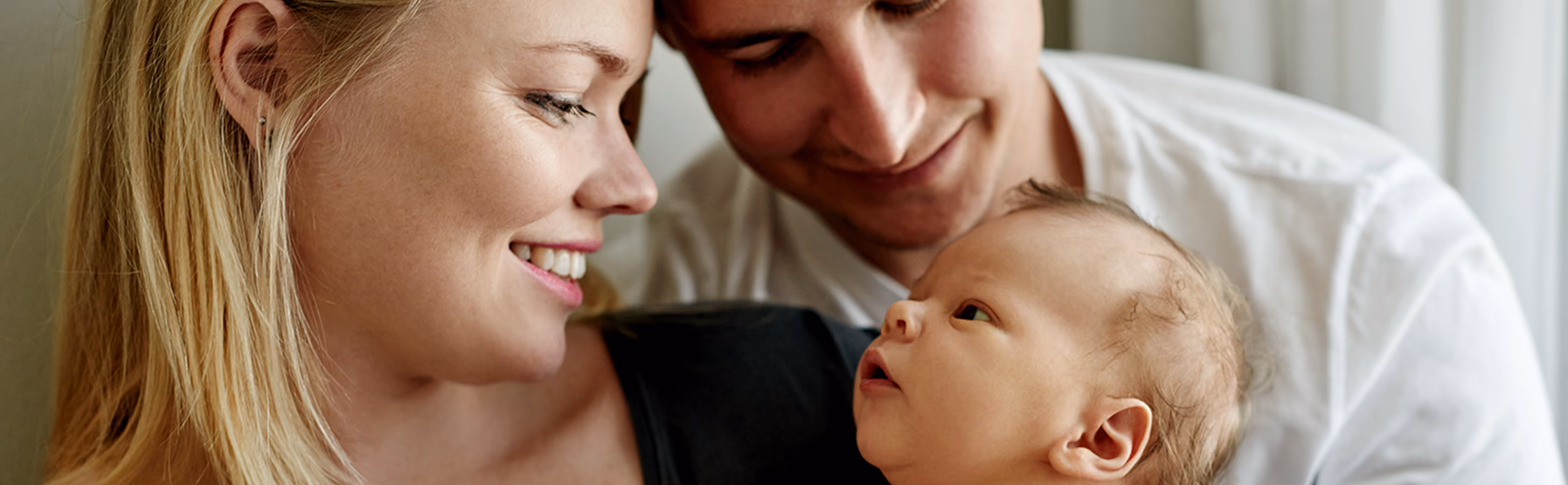 Man and woman smile as they hold their newborn baby