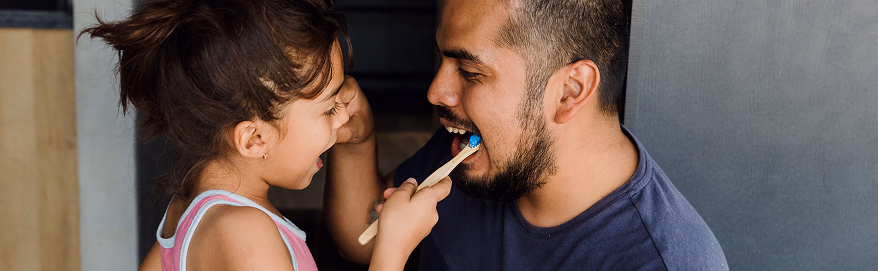 Little girl brushing her dad's teeth