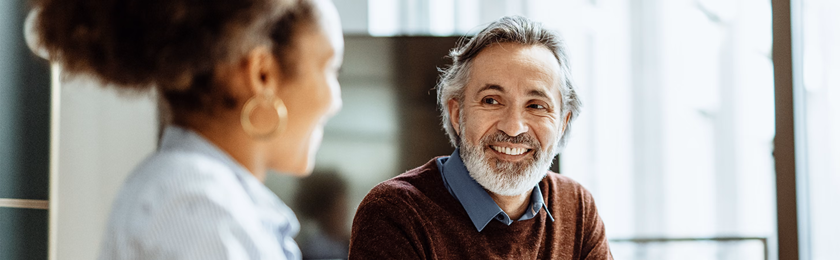 Older man with a beard talking with a healthcare professional