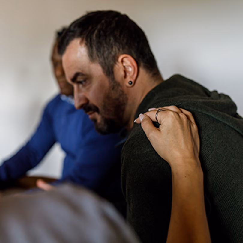 Man with schizophrenia in a white shirt holding his head in his hand