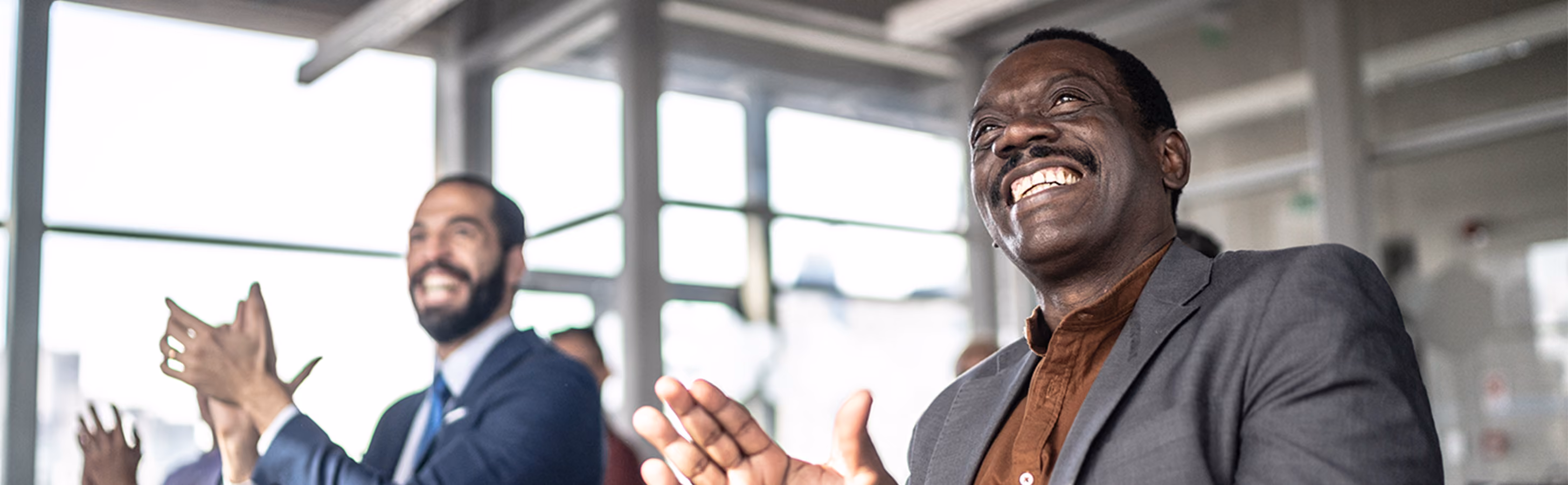 Two men clapping to congratulate a work colleague
