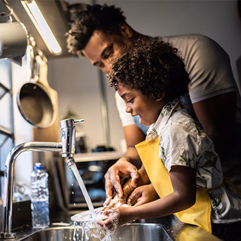 dad washes the dishes with his young son