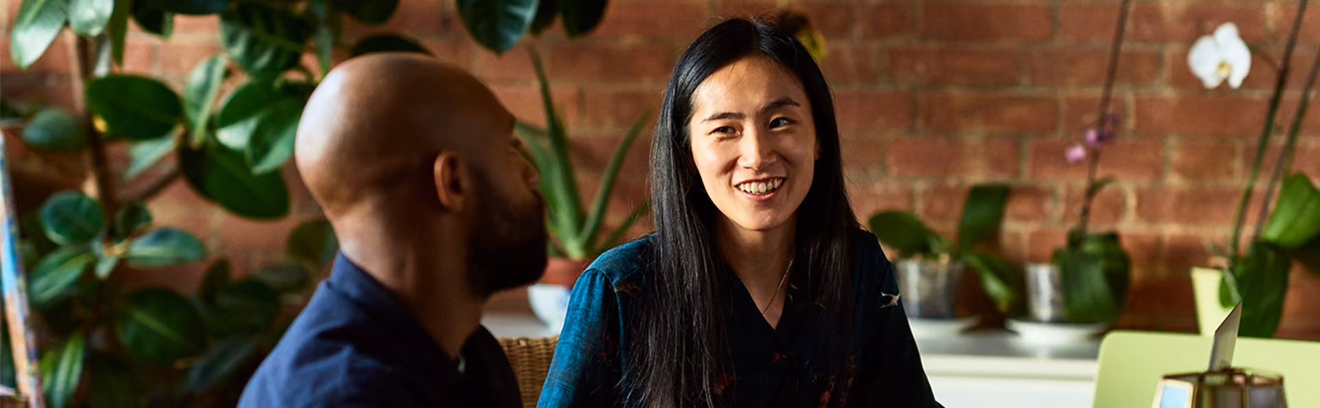 A woman smiles at a man as they talk in the office