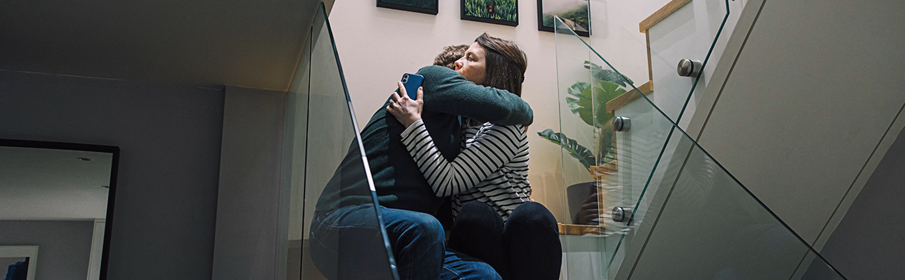 man and woman sit on stairs comforting each other by hugging