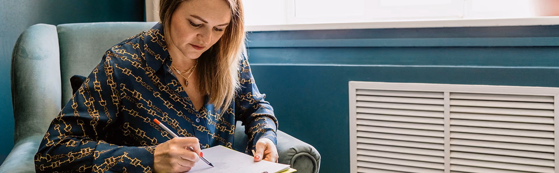 Woman sitting down writing her goals in a notebook