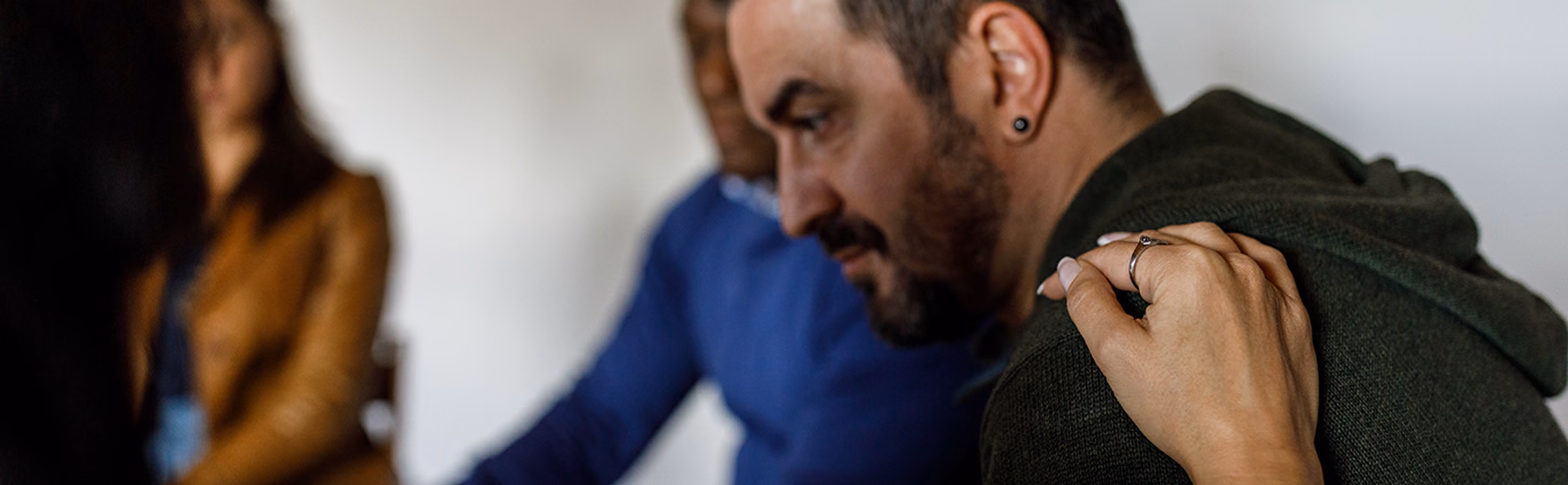 A woman comforts a man struggling with suicidal thoughts by putting her hand on his shoulder 
