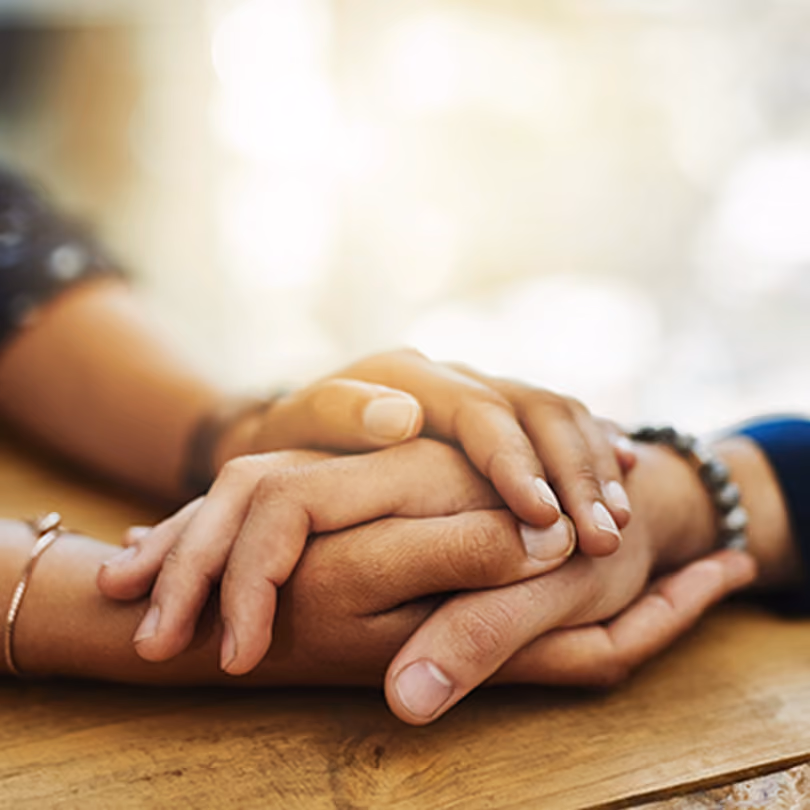 A woman comforting a man with her hands on a table
