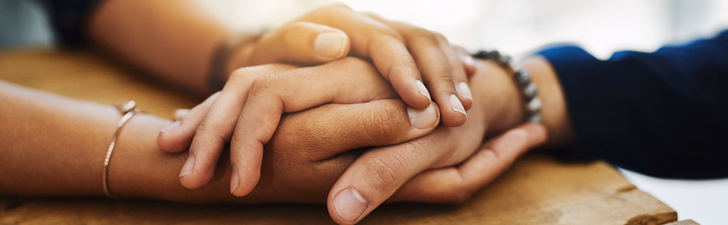 A woman comforting a man with her hands on a table