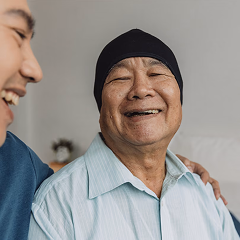A woman dealing with cancer smiling as she's comforted by her caregiver