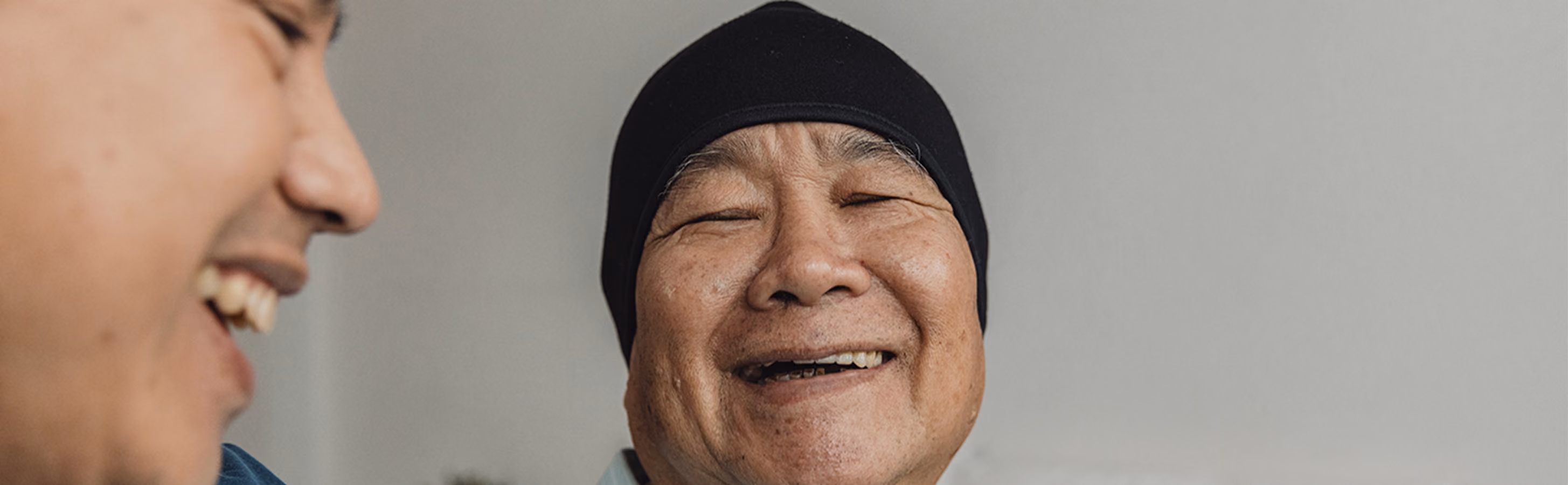 A woman dealing with cancer smiling as she's comforted by her caregiver