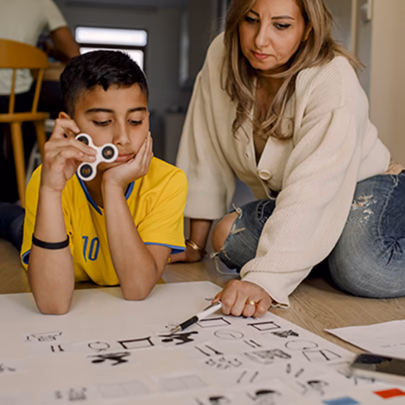 mom helps son with homework as he plays with a fidget spinner