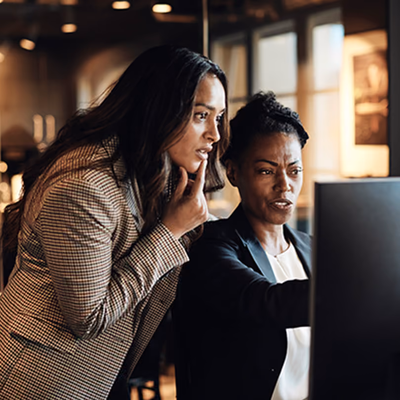 A female manager discussing a work topic with a female employee in the office
