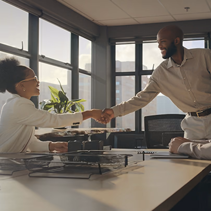 A businessman shakes hands with a businesswoman as they prepare for a meeting
