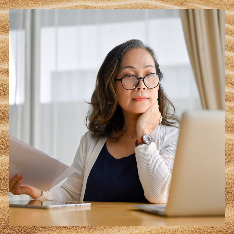Woman working at her desk as reviews paper documents and her computer