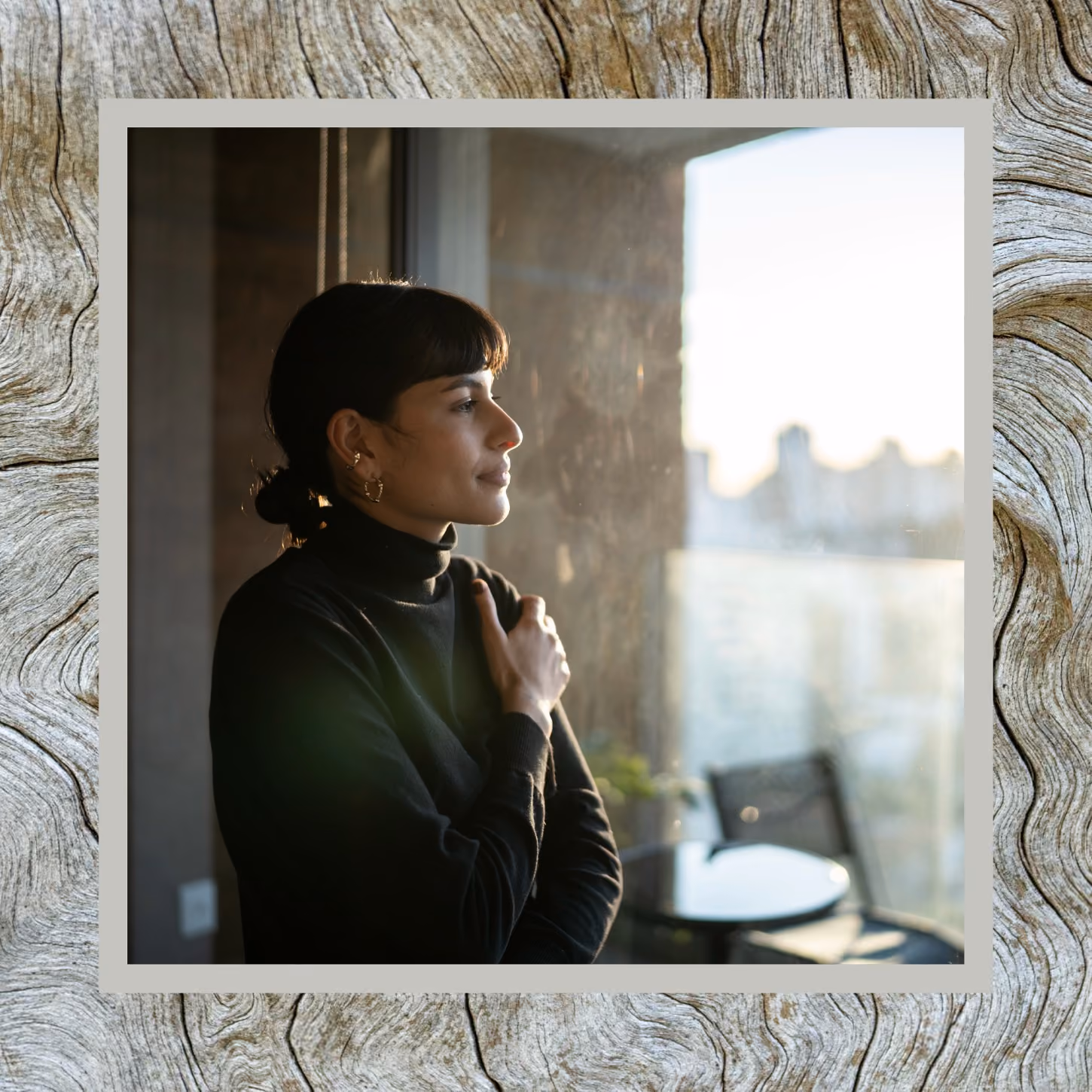 Woman holds herself as she stares out office window