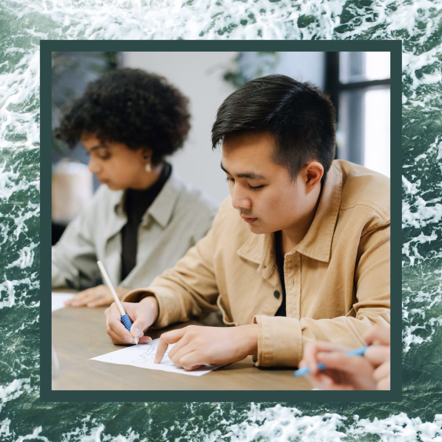 An Asian man writing notes on paper at a table