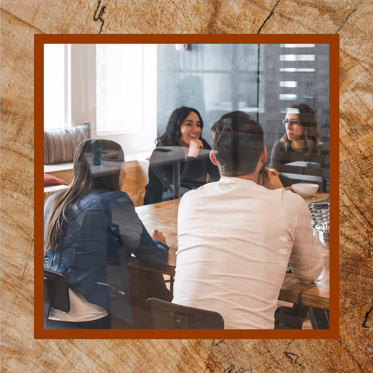 Four employees sit around a meeting table discussing work