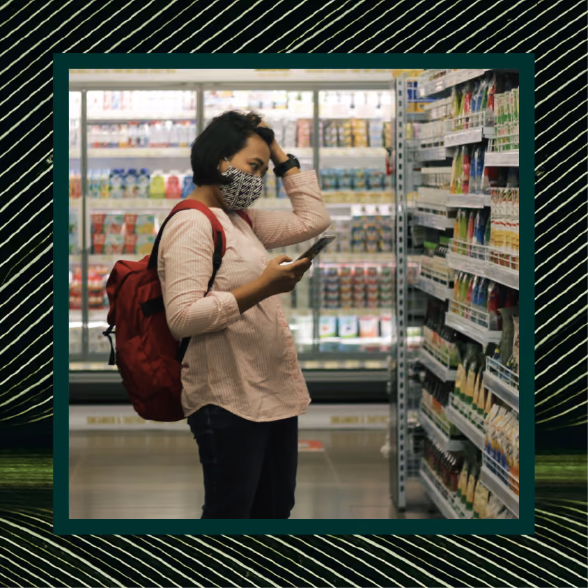 A woman checks her phone while shopping at the grocery store