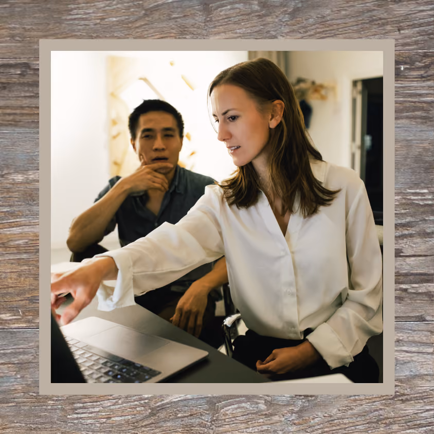 A woman shows a man a work project on her computer