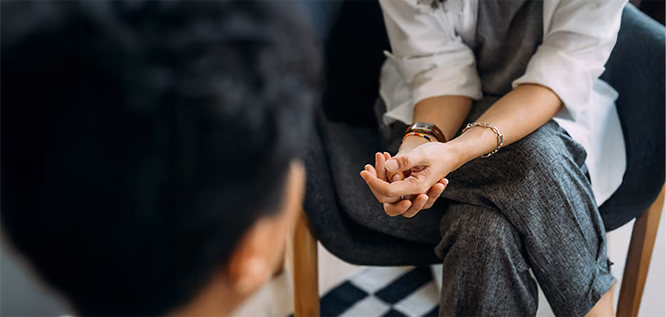 Person with folded hands listening to someone