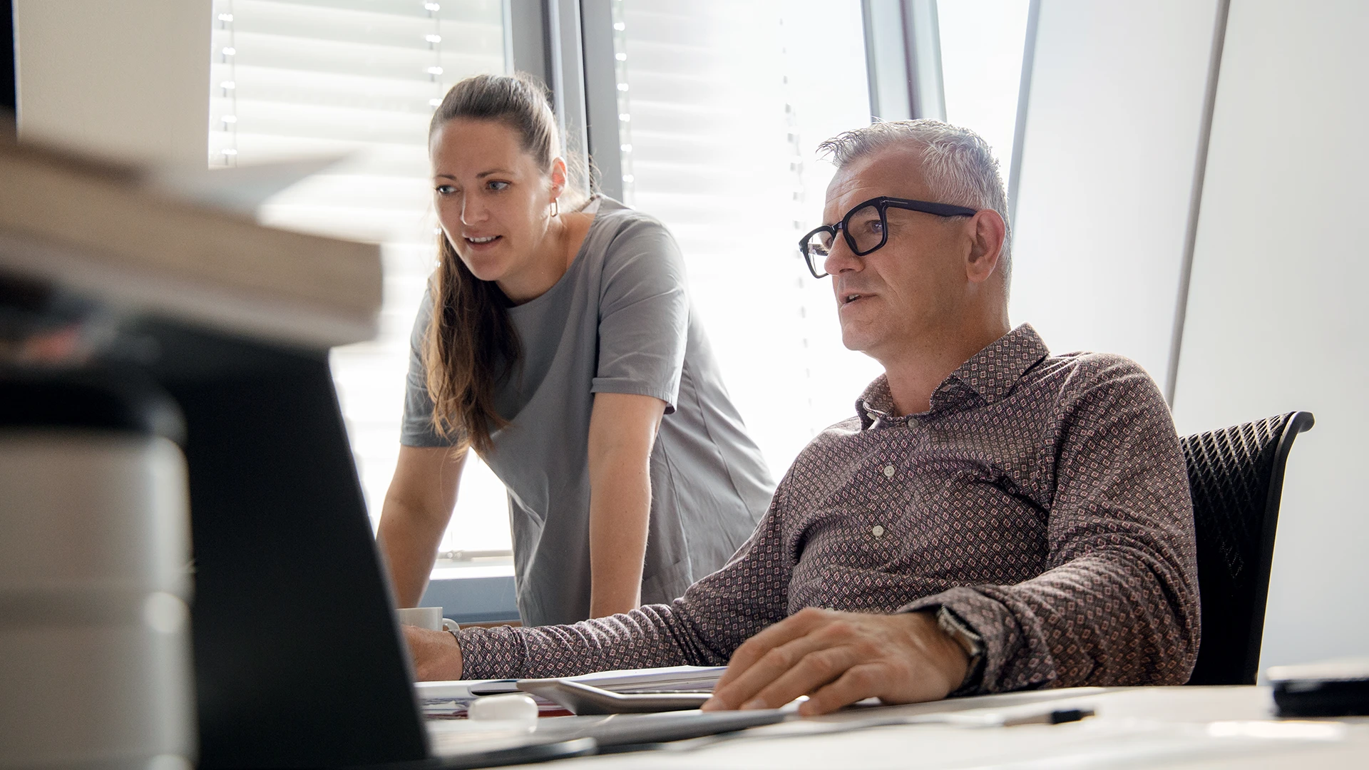 Zwei Personen tauschen sich vor einem PC aus