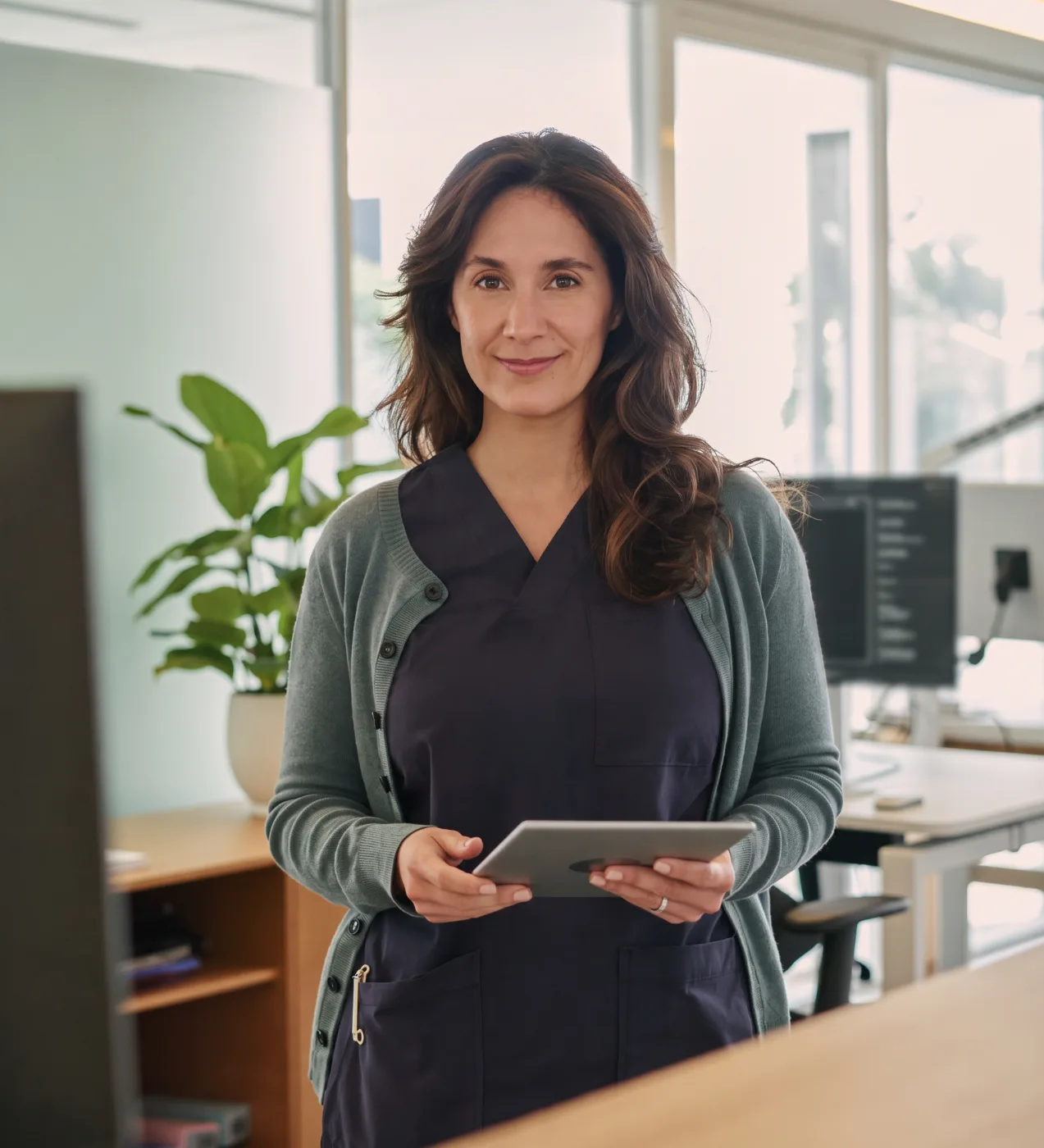 A medical practice administrator holding a tablet in her clinic's back office