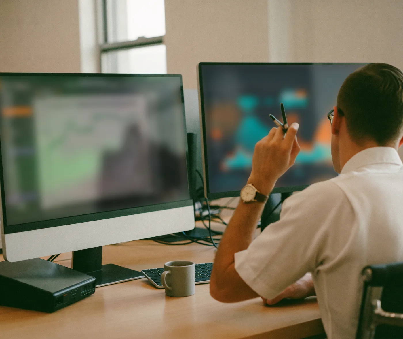 A SaaS finance manager reviewing revenue recognition schedules on two monitors