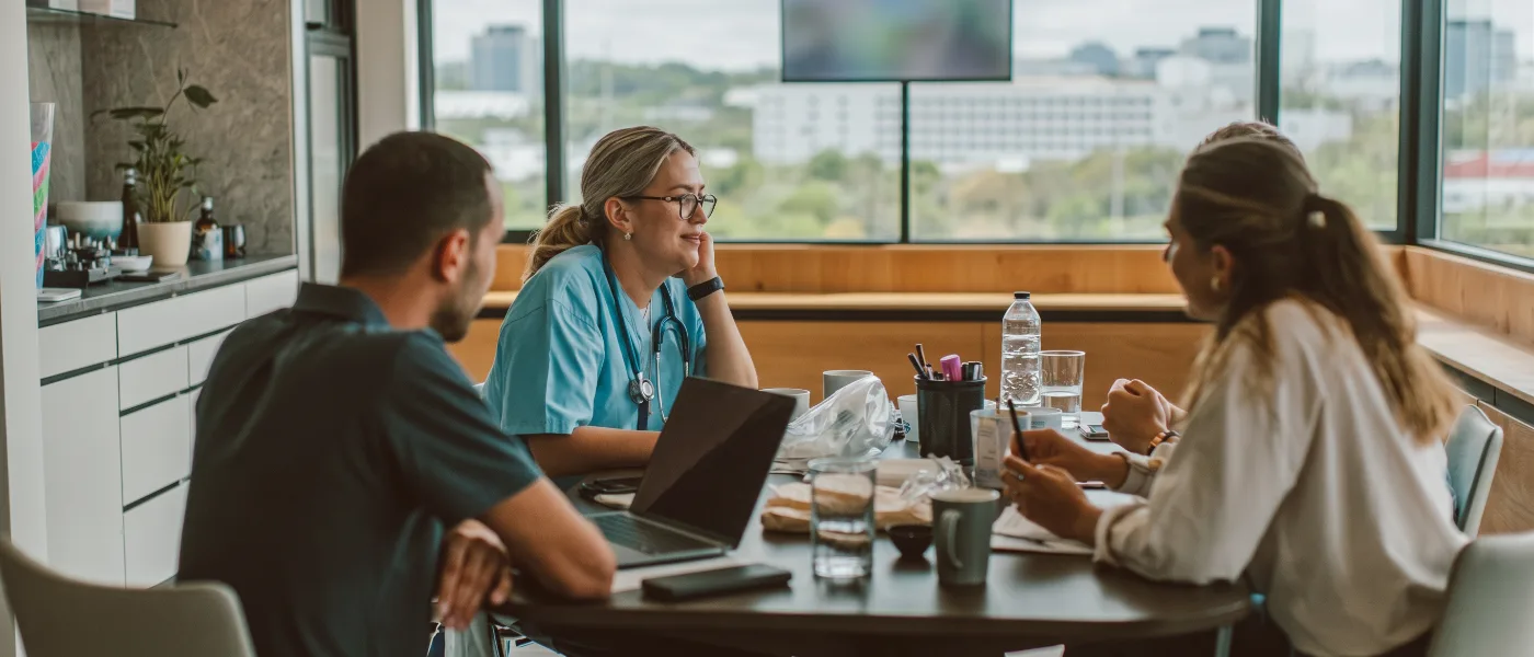 A healthcare practice team talking around a table in the clinic break room