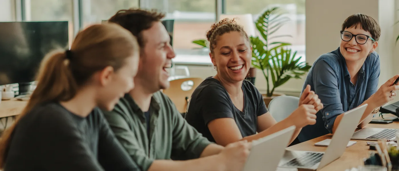 A small startup team laughing during a stand-up meeting