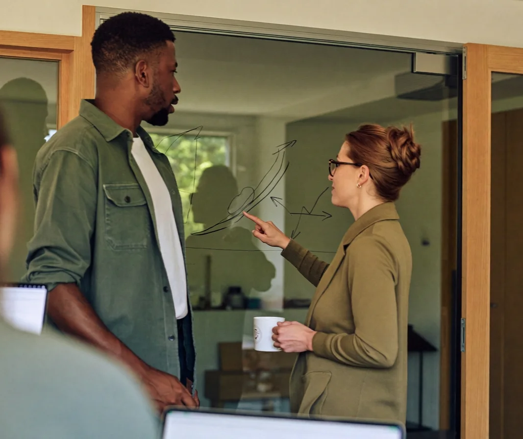 Two startup co-founders discussing a chart at a glass wall
