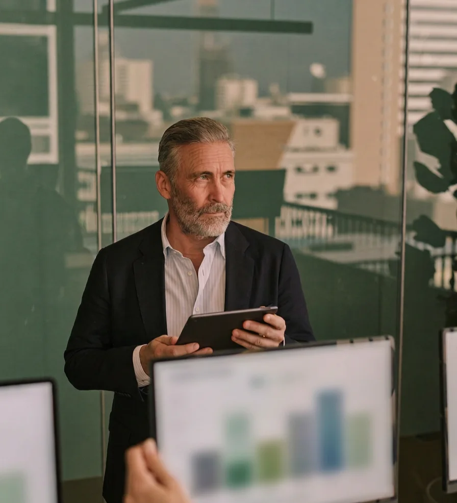 A CFO holding a tablet in a glass-walled office